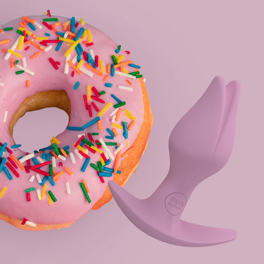 Bootie Fem butt plug by Fun Factory next to a donut on a pink background