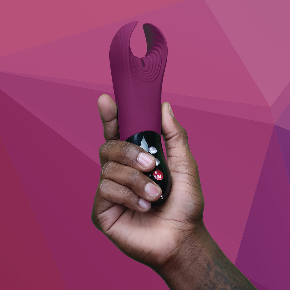 hand holding MANTA in Garnet against a purple geometric background